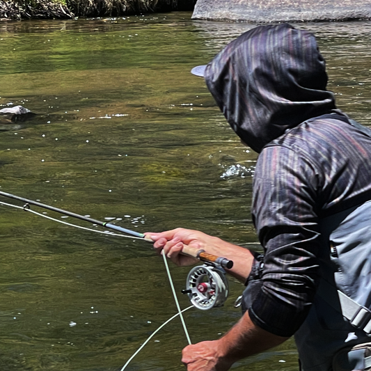 Man fly fishing in Eleven Mile Canyon wearing the  Headwater Canyon Headwaters Sun Hoodie.  Performance USA made sun protection hooded shirt.