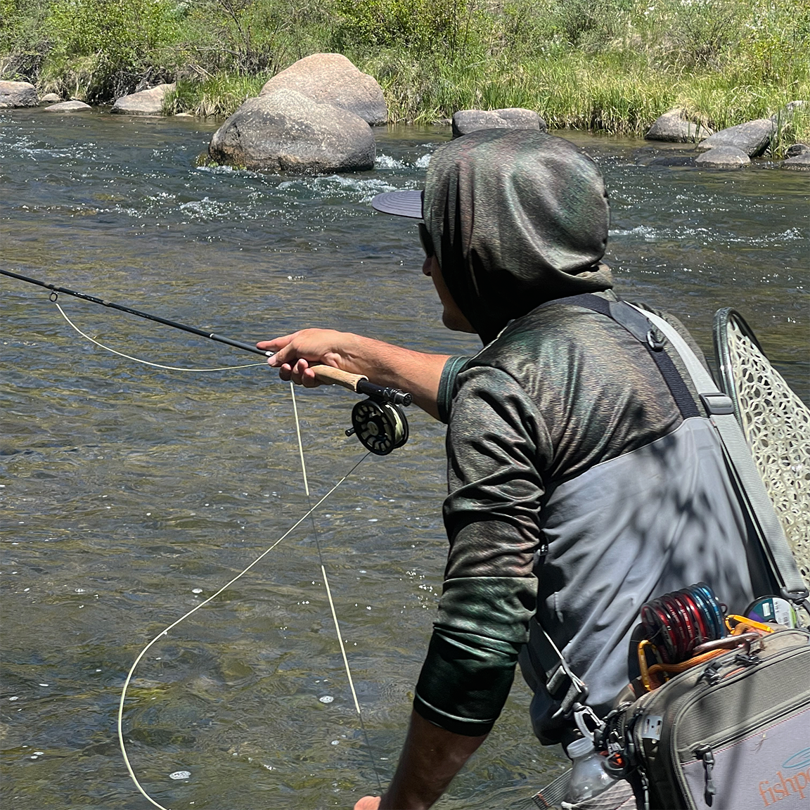 Fly fisher on the river fishing while wearing the  Headwater Canyon Adventurer Sun Hoodie.  Performance USA made sun protection hooded shirt.