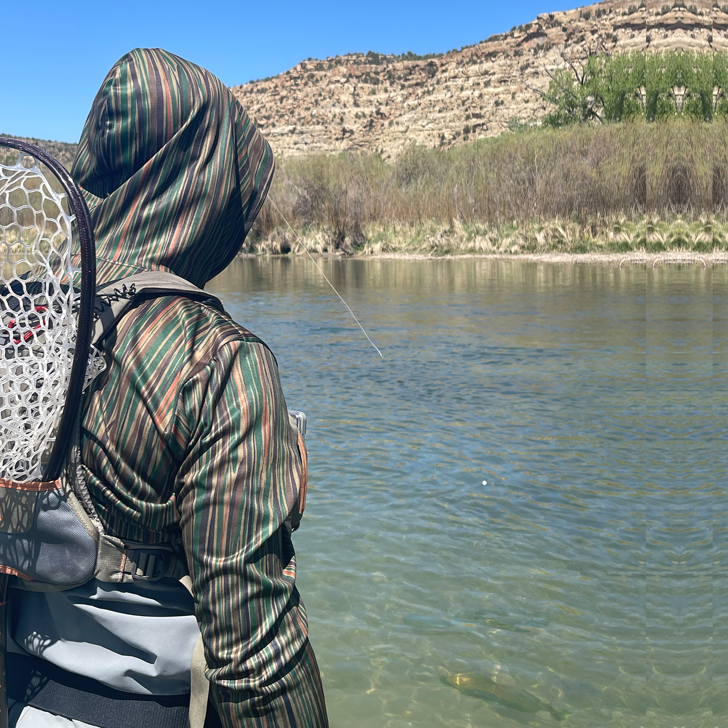 Man fly fishing in the San Juan River wearing the Headwater Canyon Tailwaters Sun Hoodie.  Performance USA made sun protection hooded shirt.